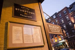 High-quality photo of Stumptown Coffee Roasters sign outside a cafe in an urban setting during evening.