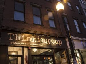 Cozy coffee shop exterior at night, warm lighting, inviting atmosphere, popular for coffee and pastries.