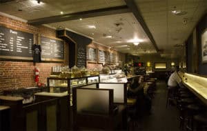 A warm, inviting cafe featuring exposed brick walls, menu boards, and a barista counter for a relaxing coffee experience.