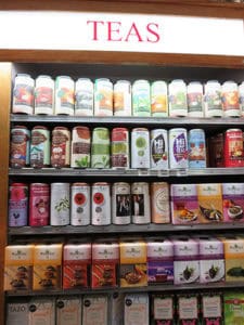 A colorful shelf of various tea brands and flavors in a retail store setting.