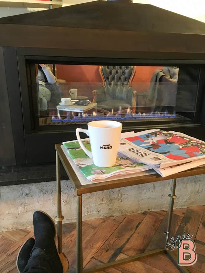 Warm fireplace with newspaper and coffee mug in cozy setting.