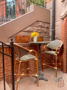 Stylish patio with two rattan chairs and a small round table with sunflowers.