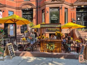 Charming outdoor cafe scene in a historic brick building with yellow umbrellas and lively patrons.