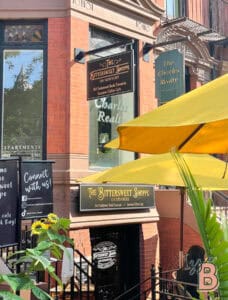 Inviting exterior of The Bittersweet Shoppe coffee shop with yellow umbrellas and vibrant flowers.