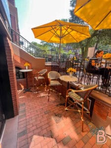 Alfresco dining area with yellow umbrellas, cozy tables, and flower decor.