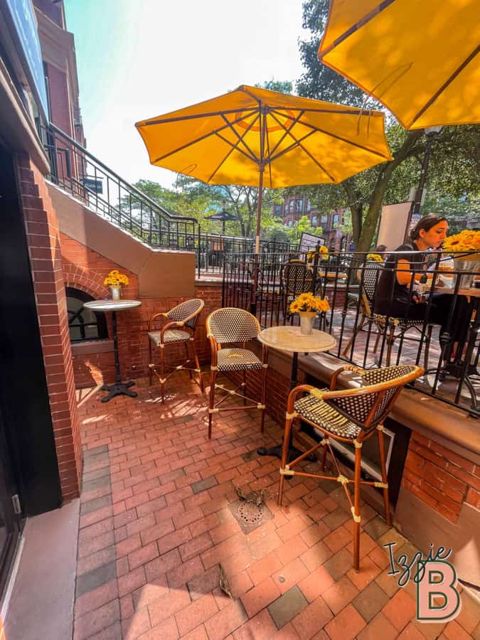 Alfresco dining area with yellow umbrellas, cozy tables, and flower decor.