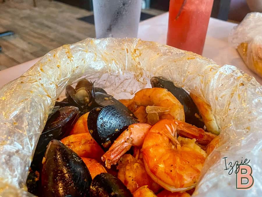 Seafood boil with shrimp, mussels, and spices in a casual dining setting.