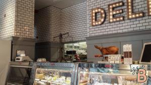 Bright deli display with meats, cheeses, and treats in a modern shop setting.