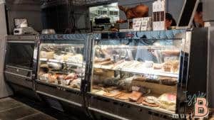 Highly detailed cheese and deli meats selection in a refrigerated display case.