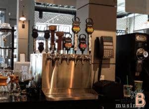 Bright brewery tap station with multiple beer taps and brewing equipment.