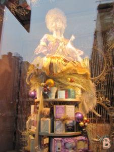 Vintage holiday mannequin with luxurious gold outfit and Christmas decorations in window display.