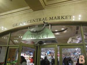 Vibrant indoor market entrance with fruits, vegetables, and shopping crowds at Grand Central Market.