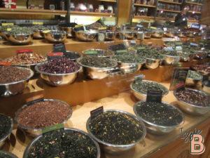 Tea shop with a variety of loose leaf teas and herbs in metal bowls for sale.