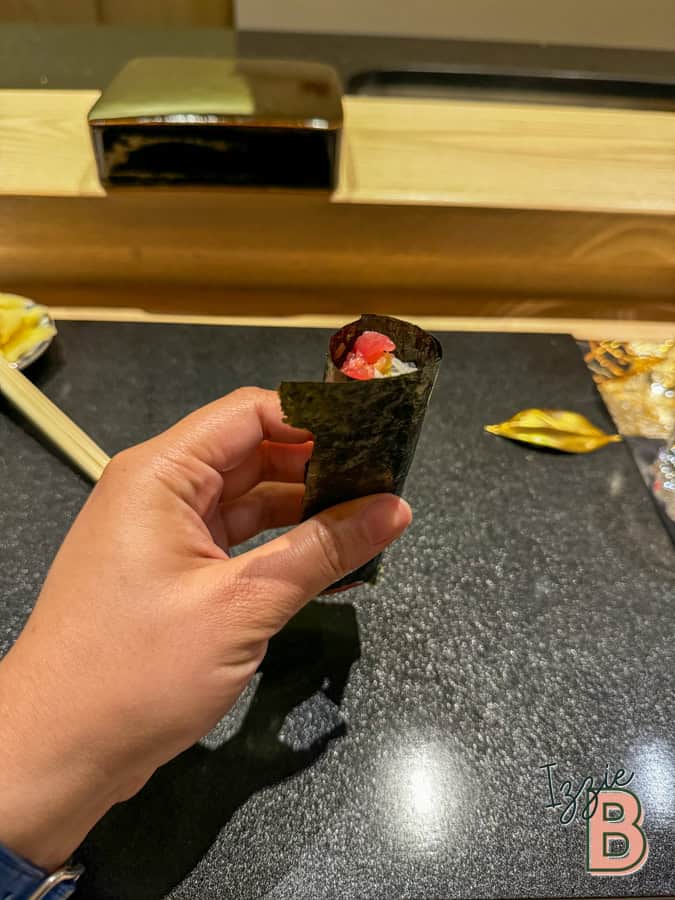 Delicious sushi roll with nori, rice, and toppings on a dark countertop at a restaurant.