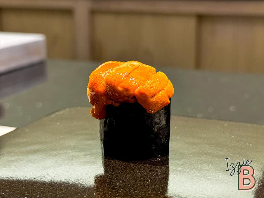 Fresh sea urchin sushi with vibrant orange roe on black nori seaweed. Perfectly plated, highlighting freshness.