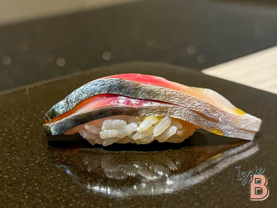 High-quality sushi featuring fresh mackerel fish on rice, served on a black plate for an authentic Japanese dining experience.