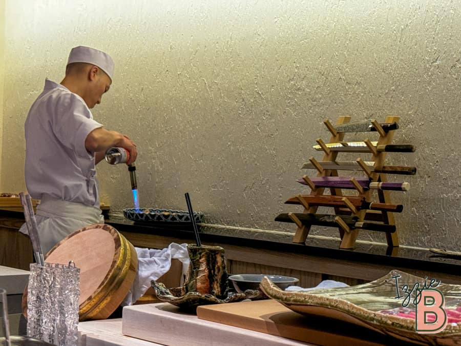 High-quality sushi chef using blowtorch to craft exquisite sushi dishes at Izzi Bytes.