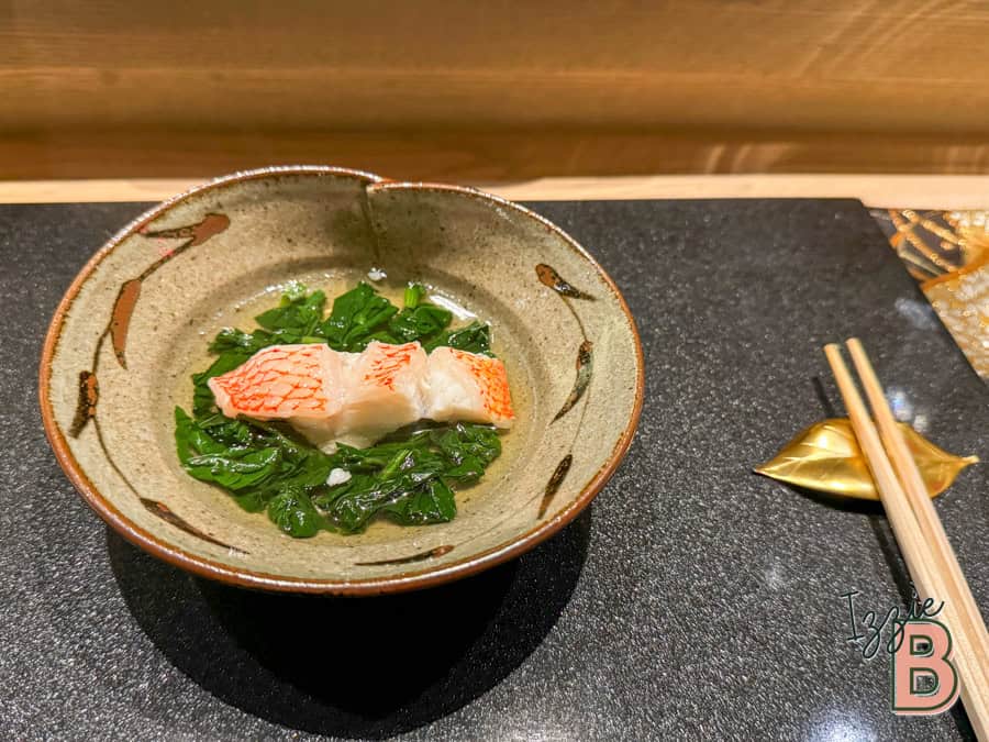 Japanese crab sashimi served with fresh greens in a rustic ceramic bowl.