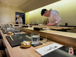 Japanese sushi chefs preparing fresh sushi in a modern restaurant setting.