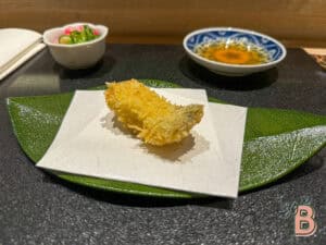 Delicious crispy tempura fish served with dipping sauce and pickled vegetables. Perfect for Japanese cuisine lovers.
