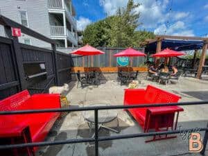 Alfresco dining setup with vibrant red benches, umbrellas, and outdoor seating for cafe or restaurant patrons.