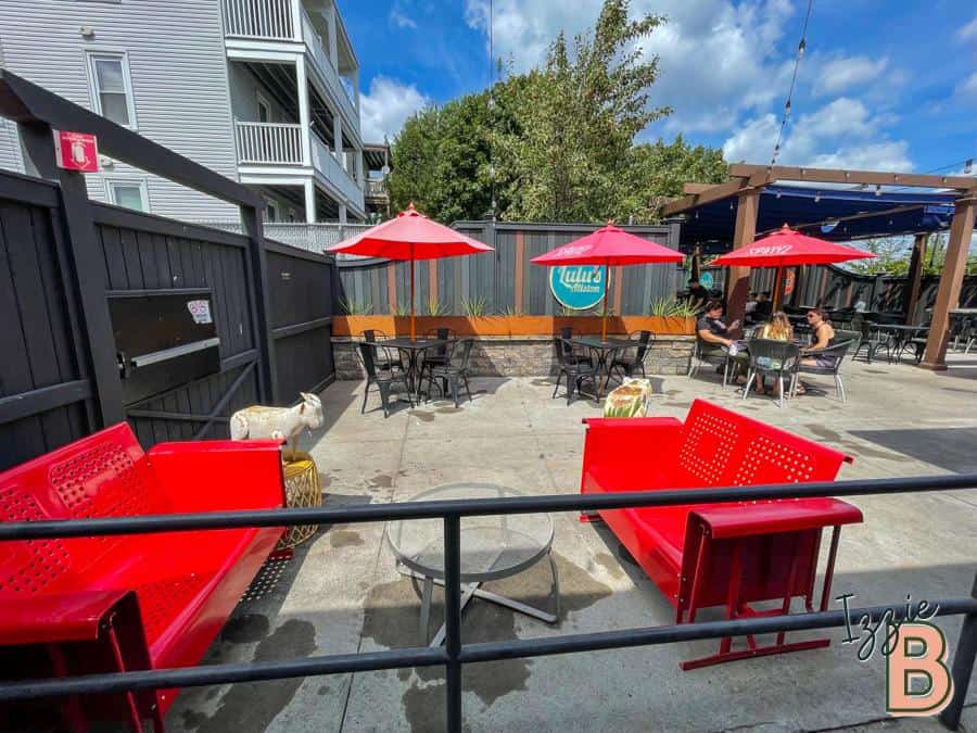 Alfresco dining setup with vibrant red benches, umbrellas, and outdoor seating for cafe or restaurant patrons.