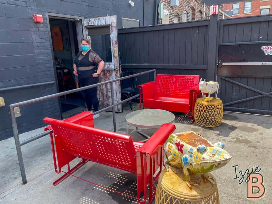 Bright outdoor seating area with colorful furniture, decorative frog sculpture, and safety measures.
