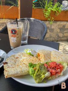 Delicious quesadilla served with fresh salsa, guacamole, iced coffee, and water at Izzie Bytes. Perfect for lunch or snack.