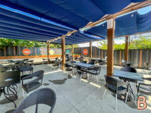 Outdoor dining area with shaded seating, modern black furniture, and vibrant atmosphere.
