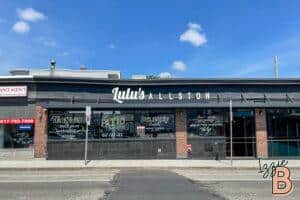 Bright daytime exterior of Lulu's Allston restaurant, showcasing takeout, dine-in, and delivery services.