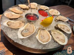 Oysters served on ice with condiments, fresh lemon, and seafood sauces for a luxurious dining experience.