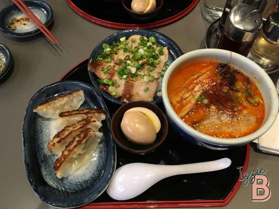 Delicious spicy ramen with toppings, gyoza dumplings, sliced pork, soy eggs, and fresh green onions, served in a Japanese restaurant.